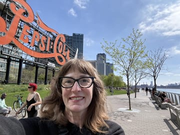 Stacy smiling beneath the historic Pepsi-Cola sign in Long Island City