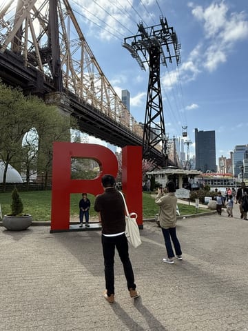Roosevelt Island sign beside a riverside path and Queensboro Bridge
