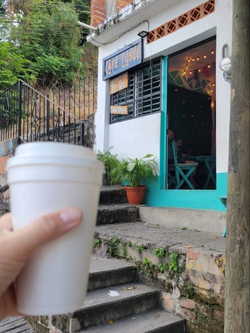 A white takeaway coffee cup outside Cafe Luslo