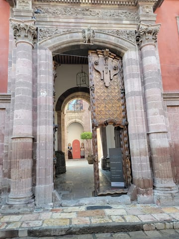 Tall carved wooden door standing open in an ornate stone museum entrance